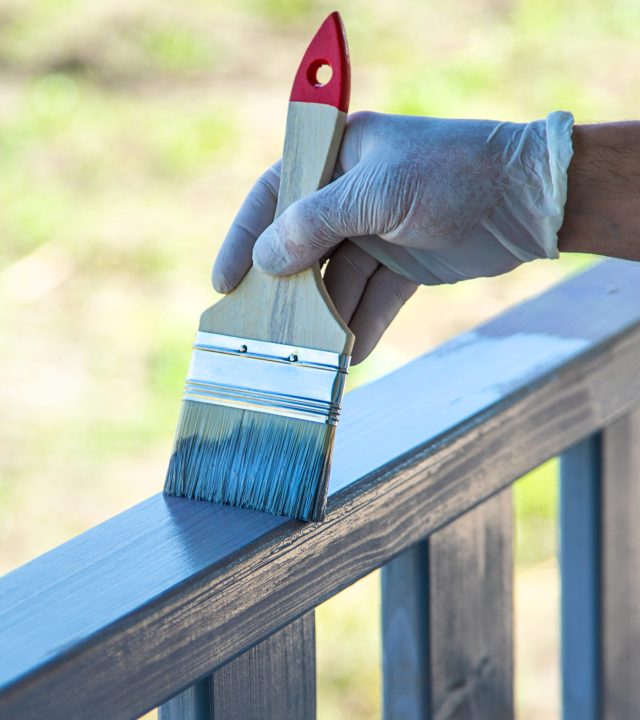 Painting a wooden board with a gray brush. Selective focus. Nature.